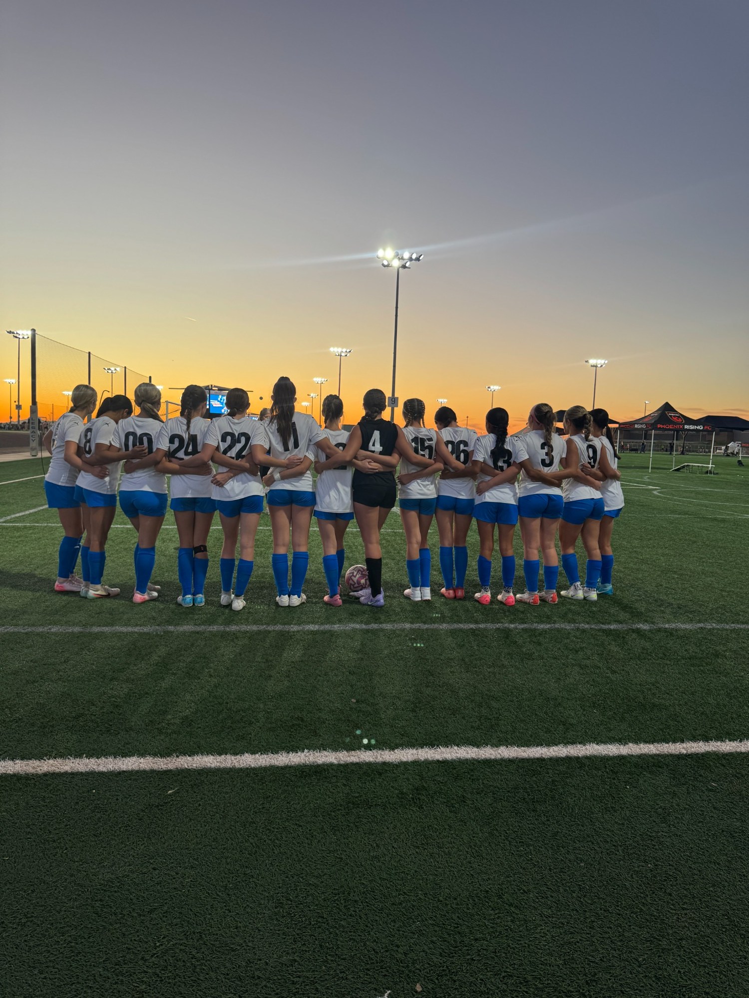 The Lady Pumas together on the field at sunset
