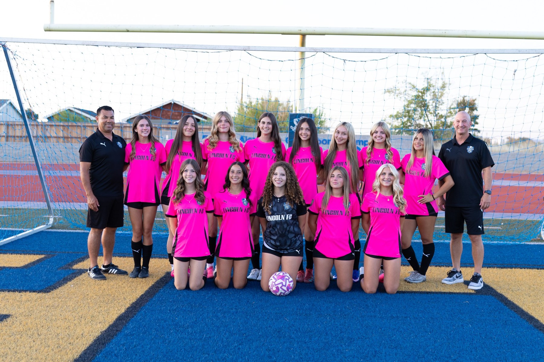 Lady Pumas players and coaches in pink uniforms